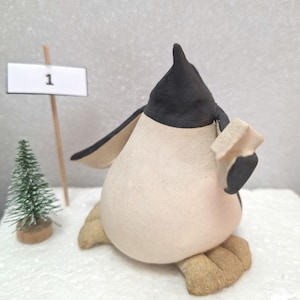 handsculpted and  handpainted ceramic penguin reading a book
