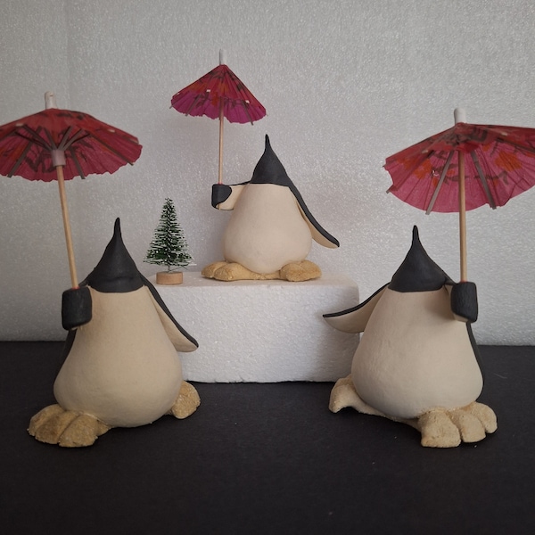 handsculpted and  handpainted ceramic penguin holding a parasol