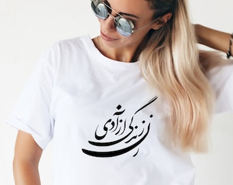 May include: White t-shirt with black Arabic calligraphy that reads "تو بودی آزادی" which translates to "You were freedom".