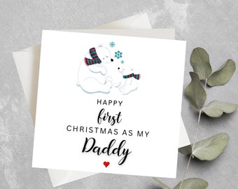 May include: A white card with two polar bears wearing scarves. The text on the card reads "Happy first Christmas as my Daddy" with a red heart.
