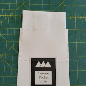 May include: White fabric square pocket with a white background and a black label that says "Square Pocket Style" with three black triangles above the text.
