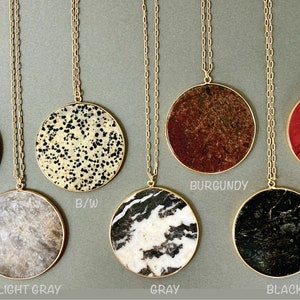 May include: Seven gold necklaces with round stone pendants. The stones are in various colors and patterns, including rose, black and white, light gray, gray, burgundy, red, and black.