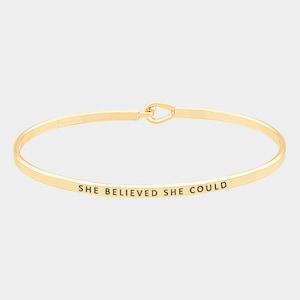 Puede incluir: Pulsera de brazalete de oro con la inscripción "She Believed She Could".