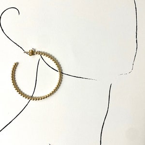 May include: Gold hoop earrings made of small beads.