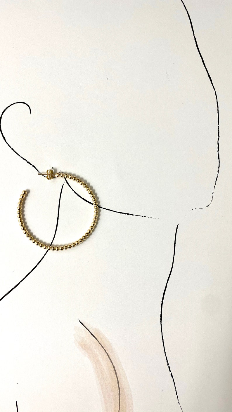 May include: Gold hoop earrings made of small beads.