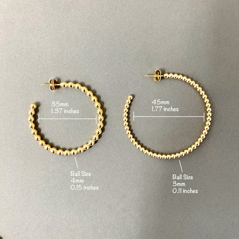 May include: Two gold hoop earrings with a beaded design. The smaller hoop is 1.37 inches in diameter with 4mm beads. The larger hoop is 1.77 inches in diameter with 3mm beads.