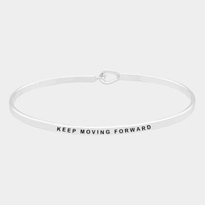 Pode incluir: Um bracelete de prata com a inscrição "KEEP MOVING FORWARD".