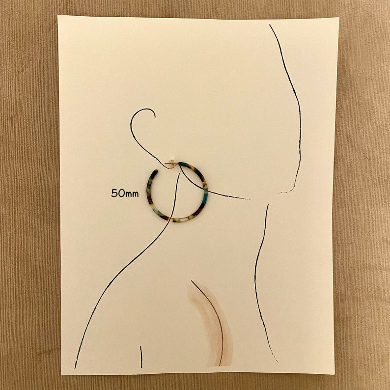 Op de afbeelding: Een paar grote, ronde, veelkleurige oorringen. De oorringen hebben een diameter van 50 mm en hebben een schildpadpatroon met blauwe en groene accenten.