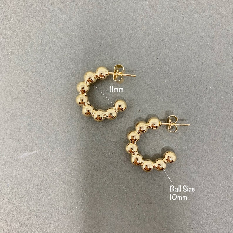 May include: A pair of gold hoop earrings with a beaded design. The earrings are 11mm in diameter and the beads are 10mm in size.