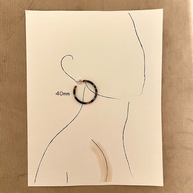 Op de afbeelding: Een paar schildpad-creolen met een diameter van 40 mm. De oorbellen worden getoond op een witte achtergrond met een lijntekening van een hoofd en schouders van een persoon.