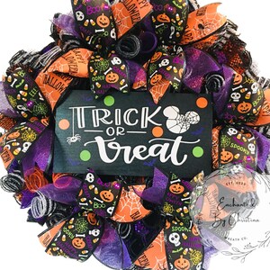 May include: A Halloween wreath with black, orange, and purple ribbon. The wreath has a sign that says "Trick or Treat" with a spider and orange and green polka dots. The wreath is decorated with various Halloween themed ribbons and mesh.