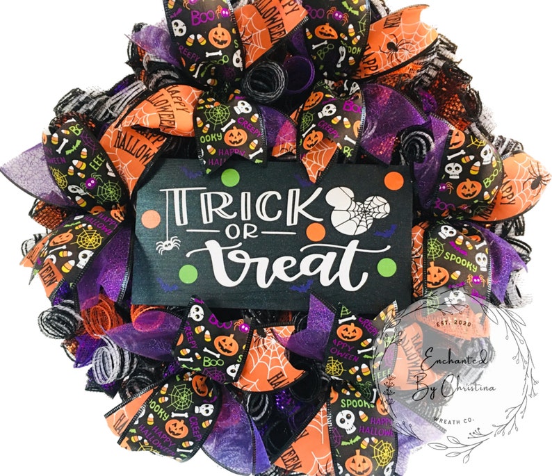 May include: A Halloween wreath with black, orange, and purple ribbon. The wreath has a sign that says "Trick or Treat" with a spider and orange and green polka dots. The wreath is decorated with various Halloween themed ribbons and mesh.