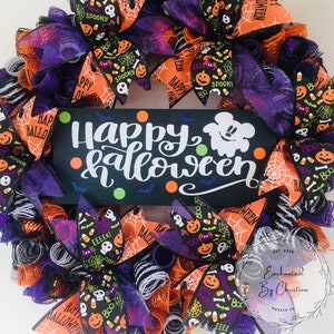 May include: A Halloween wreath with orange, black, and purple mesh and ribbons. The wreath features a sign that says "Happy Halloween" with a Mickey Mouse ghost. The wreath is decorated with various Halloween-themed patterns, including pumpkins, candy corn, and bats.