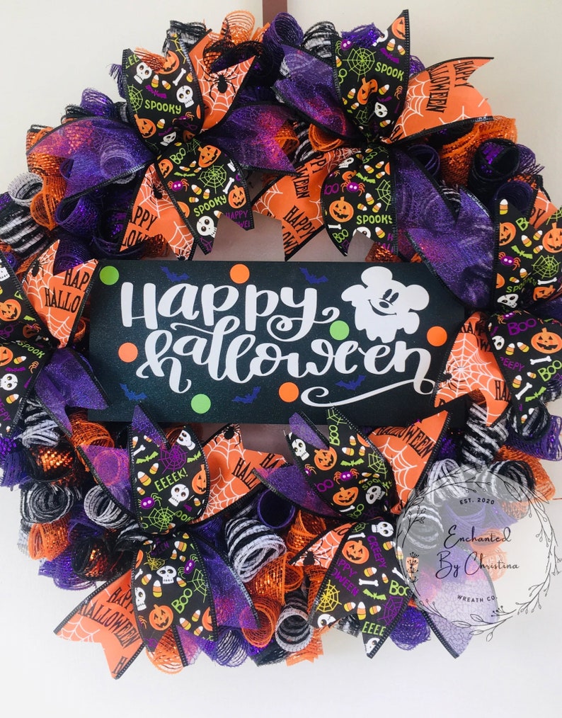 May include: A Halloween wreath with orange, black, and purple mesh and ribbons. The wreath features a sign that says "Happy Halloween" with a Mickey Mouse ghost. The wreath is decorated with various Halloween-themed patterns, including pumpkins, candy corn, and bats.