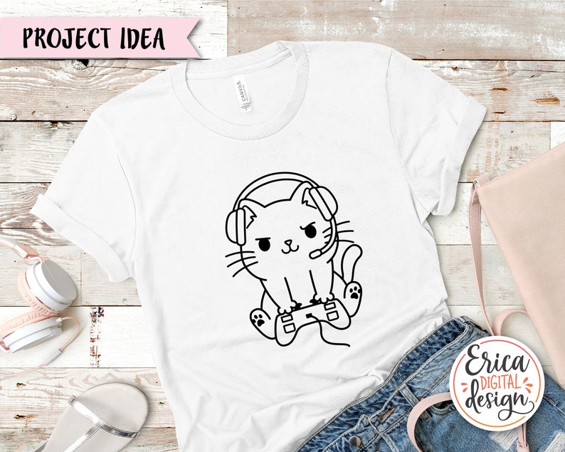 Puede incluir: Camiseta blanca con un dibujo de l&iacute;nea negra de un gato con auriculares y sosteniendo un mando de videojuego. El texto "Project Idea" est&aacute; en la parte superior de la imagen.