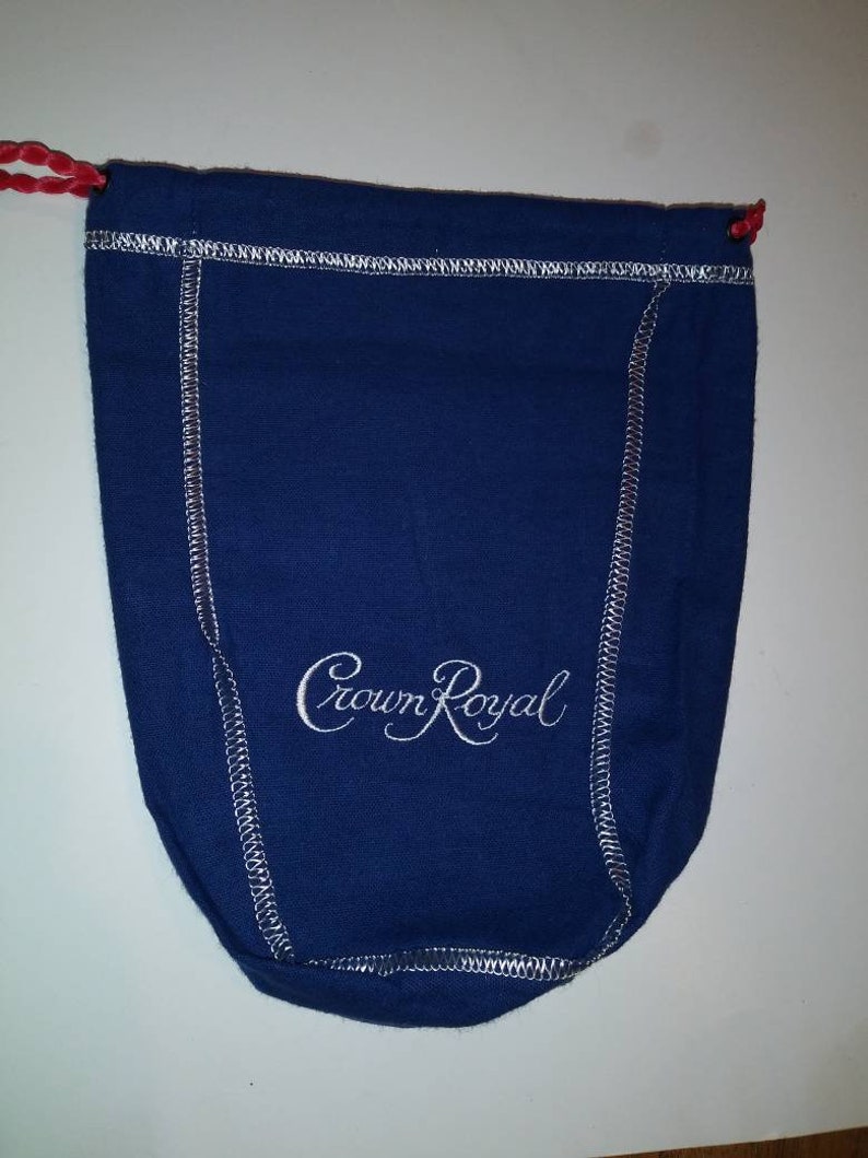 May include: A blue drawstring bag with white stitching and the words "Crown Royal" embroidered in white.