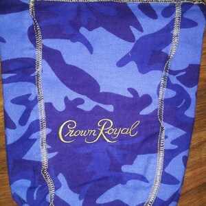 May include: Blue and purple camouflage fabric bag with gold stitching and the words "Crown Royal" embroidered in gold.