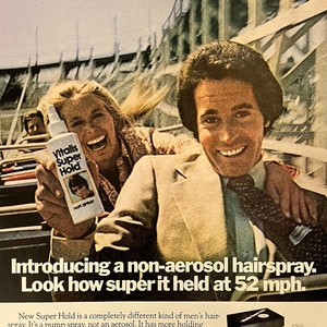 May include: A vintage advertisement for Vitalis Super Hold hairspray. The ad features a couple riding a roller coaster with the text "Introducing a non-aerosol hairspray. Look how super it held at 52 mph." and "New Vitalis Super Hold."