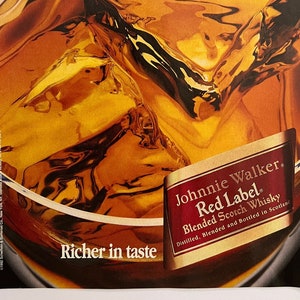 May include: A close-up of a glass of amber-colored liquid with ice cubes. The glass is partially obscured by a label that reads "Johnnie Walker. Red Label. Blended Scotch Whisky. Distilled, Blended and Bottled in Scotland." The text "Savor the richness of Red." is at the top of the image. The text "Richer in taste" is at the bottom of the image.