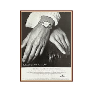 May include: Black and white advertisement featuring a Rolex watch on a wrist. The watch has a silver band and a round face. The image includes the text "The hands, Virginia Wade. The watch, Rolex."