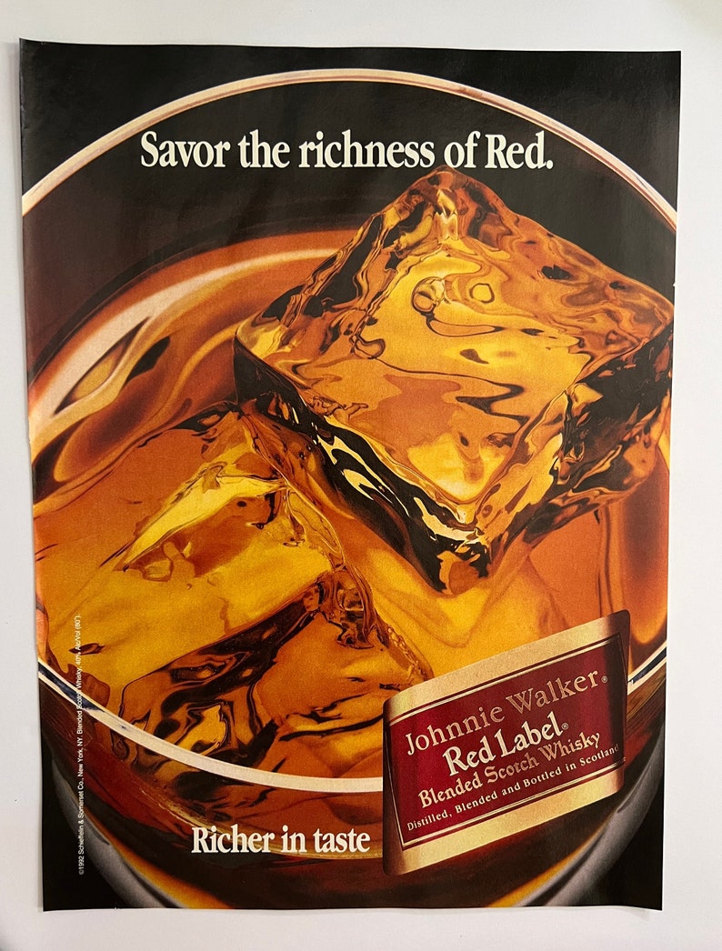 May include: A close-up of a glass of amber-colored liquid with ice cubes. The glass is partially obscured by a label that reads "Johnnie Walker. Red Label. Blended Scotch Whisky. Distilled, Blended and Bottled in Scotland." The text "Savor the richness of Red." is at the top of the image. The text "Richer in taste" is at the bottom of the image.