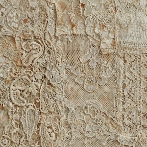 Könnte beinhalten: Nahaufnahme von antiker Spitze mit komplizierten Mustern und Texturen. Die cremefarbene Spitze zeigt florale und geometrische Designs, mit Variationen im Gewebe und einigen Verfärbungen, die auf Alter und Gebrauch hindeuten.