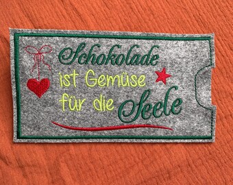 Könnte beinhalten: Ein grauer Filz-Patch mit grüner Naht um die Ränder. Der Patch hat ein rotes Herz, einen roten Stern und eine grüne und gelbe Stickerei, die "Schokolade ist Gemäse für die Seele" lautet.