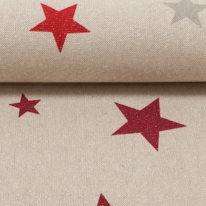 Könnte beinhalten: Beigefarbener Stoff mit einem sich wiederholenden Muster aus roten Sternen. Die Sterne sind in der Mitte etwas dunkler rot und haben einen glitzernden Überzug.