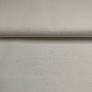 Könnte beinhalten: Nahaufnahme eines weißen Stoffes mit glatter Textur. Der Stoff ist in der Mitte gefaltet, so dass die Innenseite der Falte sichtbar ist.