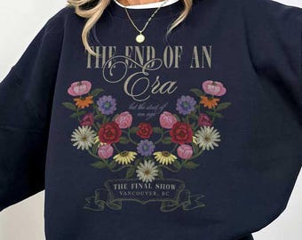Puede incluir: Sudadera azul marino con diseño floral y texto "THE END OF AN Ora". El diseño floral incluye flores rosas, rojas y amarillas. También es visible el texto "THE FINAL SHOW VANCOUVER BC".