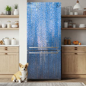 May include: A refrigerator with a blue floral design, featuring a cascading wisteria pattern. The image shows a stainless steel handle and a corgi dog sitting on a rug in front of the refrigerator. The kitchen has wooden cabinets and shelves.