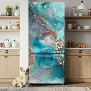 A dog sits in front of a refrigerator with a marble-like design in shades of blue and gold. The kitchen features wooden cabinets, shelves, and various kitchen items such as bowls, cups, and oranges.