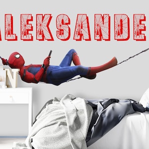 May include: A red and blue Spiderman character is hanging from a web line with the name "ALEKSANDER" written in red letters with a spiderweb design.