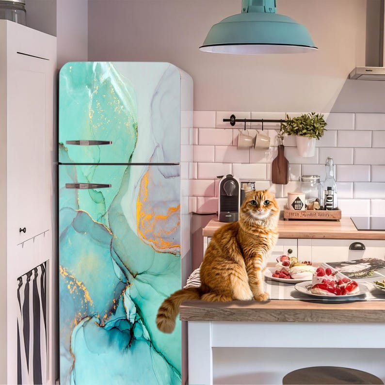 A cat sits on a kitchen counter, surrounded by various kitchen items such as a refrigerator, potted plant, and other appliances.