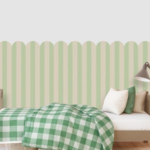 May include: A child's bed with a green and white checkered blanket and pillows. The wall behind the bed has a green and beige striped pattern. A gray lamp is next to the bed.