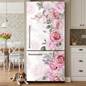 May include: A refrigerator featuring a white background decorated with a large, vibrant floral print of pink and white roses with green leaves. The appliance has a top-mounted freezer section, a bottom refrigerator section, and silver handles.