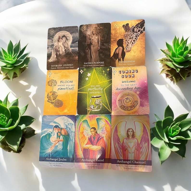 Op de afbeelding: Een set van 10 orakelkaarten met kleurrijke illustraties en tekst. De kaarten bevatten afbeeldingen van engelen, een giraffe, een bloeiende bloem en een vrouw met een kroon. De tekst op de kaarten bevat zinnen als "Sjamanistische Reis", "Heilig Doel", "Bloei waar je geplant bent" en "Binnenkort".