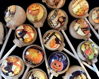 Puede incluir: Surtido de piruletas redondas con temática de Halloween en palos. Las piruletas presentan varias imágenes, incluyendo calabazas, brujas, murciélagos y las palabras "Happy Halloween".