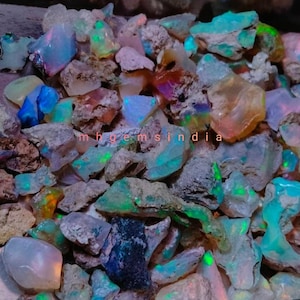 May include: A collection of rough opal gemstones in various shades of blue, green, and white. The opals are raw and have a natural, earthy appearance.