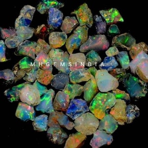 May include: A collection of rough, natural opal gemstones in various shades of green, blue, and white with iridescent flashes. The opals are irregular in shape and size, and some have a rough, textured surface. The text "MHGEMSINDIA" is visible in the image.