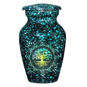 Op de afbeelding: Een kleine, teal en zwarte urn met een levensboomontwerp. De urn heeft een gespikkelde afwerking en een deksel.