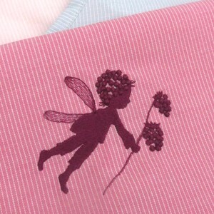Könnte beinhalten: Drei Schürzen und ein passendes Geschirrtuch in Rosa, Hellrosa und Hellblau, jeweils mit einem gestickten Feen-Design. Die Schürzen haben ein Streifenmuster, und die Fee hält eine Blume. Die Schürzen sind aus weichem Stoff.