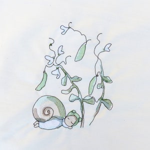 Könnte beinhalten: Ein weißer Stoff mit einer handgezeichneten Illustration einer schlafenden Schnecke unter einer grünen Erbsenpflanze mit weißen Blüten.