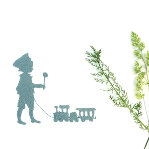 May include: A blue silhouette of a child pulling a toy train on a white background.  The child is holding a flag in their right hand.  There are three green plants on the right side of the image.