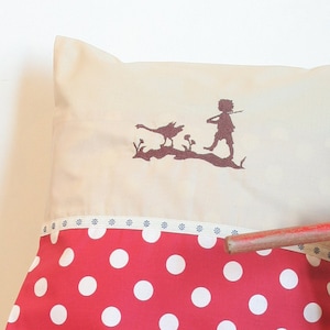 May include: A wooden toy wagon with red and white polka dot fabric and a white pillow with a silhouette of a child and a goose.