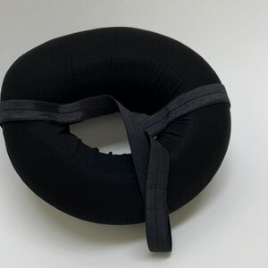 May include: Black donut-shaped cushion with a black elastic strap.