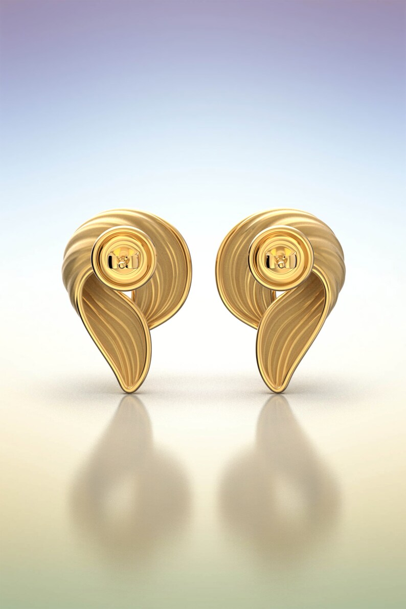 Puede incluir: Un par de pendientes de oro con un dise&ntilde;o retorcido en forma de onda. Los pendientes tienen un peque&ntilde;o bot&oacute;n redondo de oro en el centro.