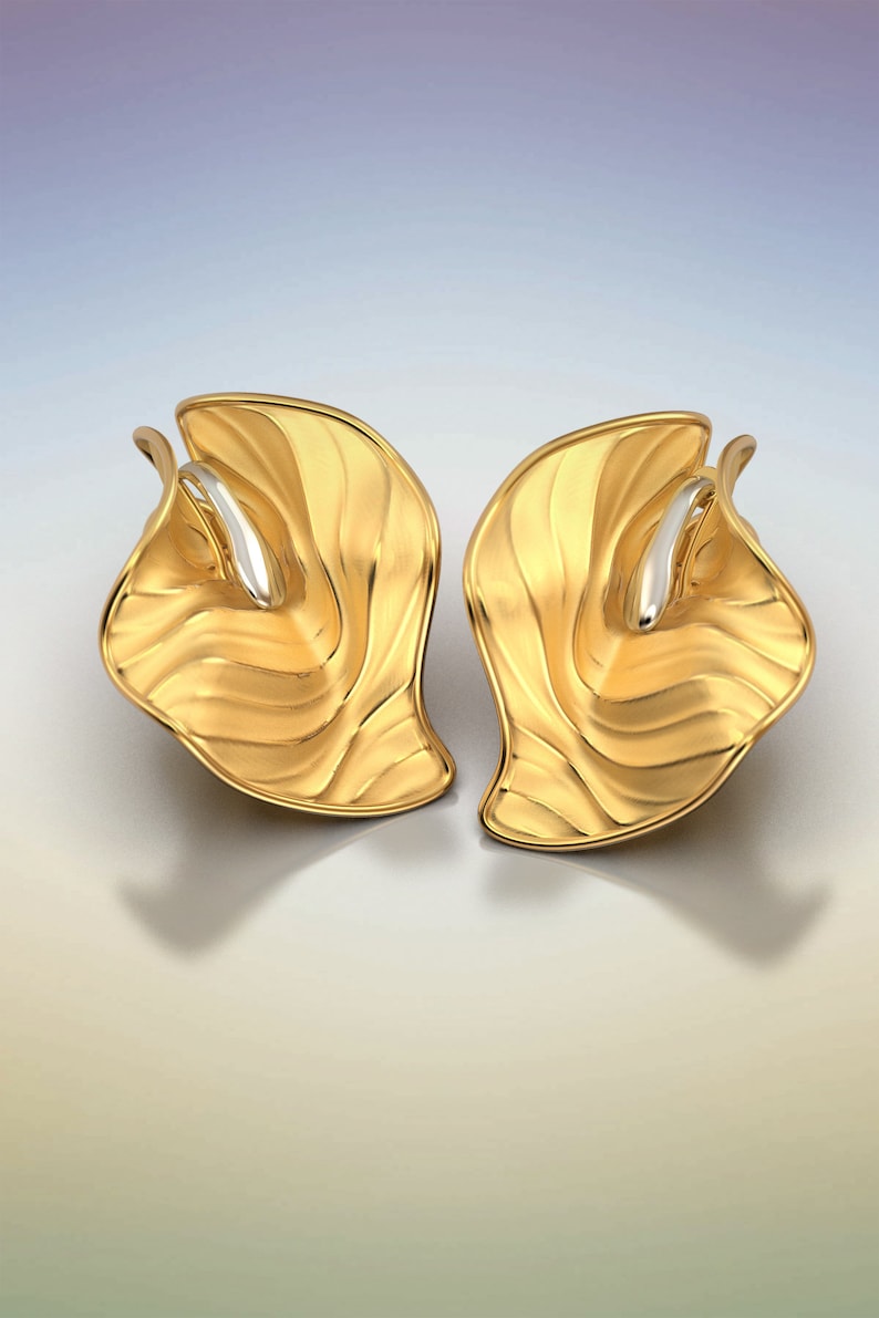Puede incluir: Un par de pendientes de oro con un dise&ntilde;o ondulado y org&aacute;nico. Los pendientes est&aacute;n hechos de dos piezas de metal que se unen en el medio. El metal es de color dorado brillante y tiene un acabado liso.