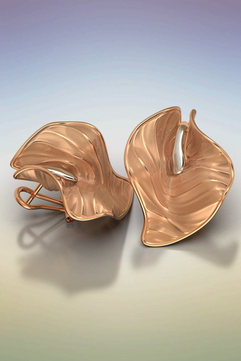 Puede incluir: Un par de pendientes de oro rosa con un dise&ntilde;o ondulado y org&aacute;nico. Los pendientes est&aacute;n hechos de metal y tienen un acabado pulido.