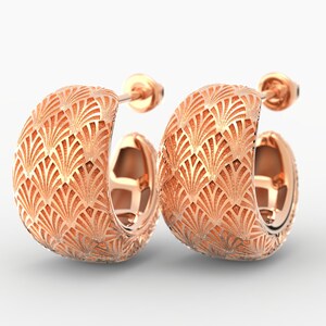 Puede incluir: Un par de pendientes de aro de oro rosa. Cada pendiente presenta un patr&oacute;n detallado en forma de abanico en su superficie. Los pendientes tienen un cierre de poste y presi&oacute;n y se muestran sobre un fondo blanco.